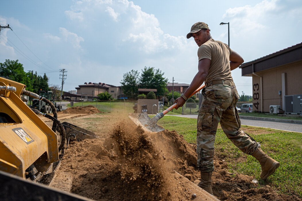 U.S. Air Force Senior Airman Abrein Dunn, 51st Civil Engineer Squadron pavements and equipment journeyman, shovels dirt during a construction project at Osan Air Base, Republic of Korea, Sept. 11, 2023. The 51st CES pavements and equipment Airmen are commonly referred to as dirt boyz, due to the hands-on nature of their jobs. Dirt Boyz are extensively trained in operating heavy construction machinery, including backhoes and excavators. These skills are invaluable for executing a wide range of construction and maintenance projects across the base, guaranteeing the 51st Fighter Wing remains mission-ready. (U.S. Air Force photo by Staff Sgt. Thomas Sjoberg)