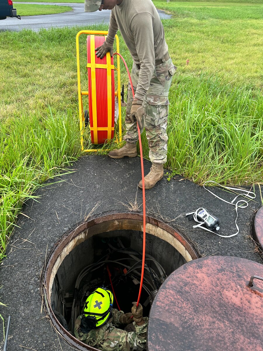 U.S. Air Force Senior Airman Carlos Reyes, 374th Communications Squadron cable antenna technician, above, feeds the pull string of a duct rodder to Airman 1st Class Gabrielle Oropesa, 374th CS cable antenna technician, at Yokota Air Base, Japan, Aug. 23, 2023. The duct router allows personnel to easily feed pull strings through manholes or other conduits to help install new communication systems. (Courtesy Photo)
