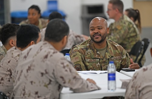 A photo of a man speaking to others around a table.