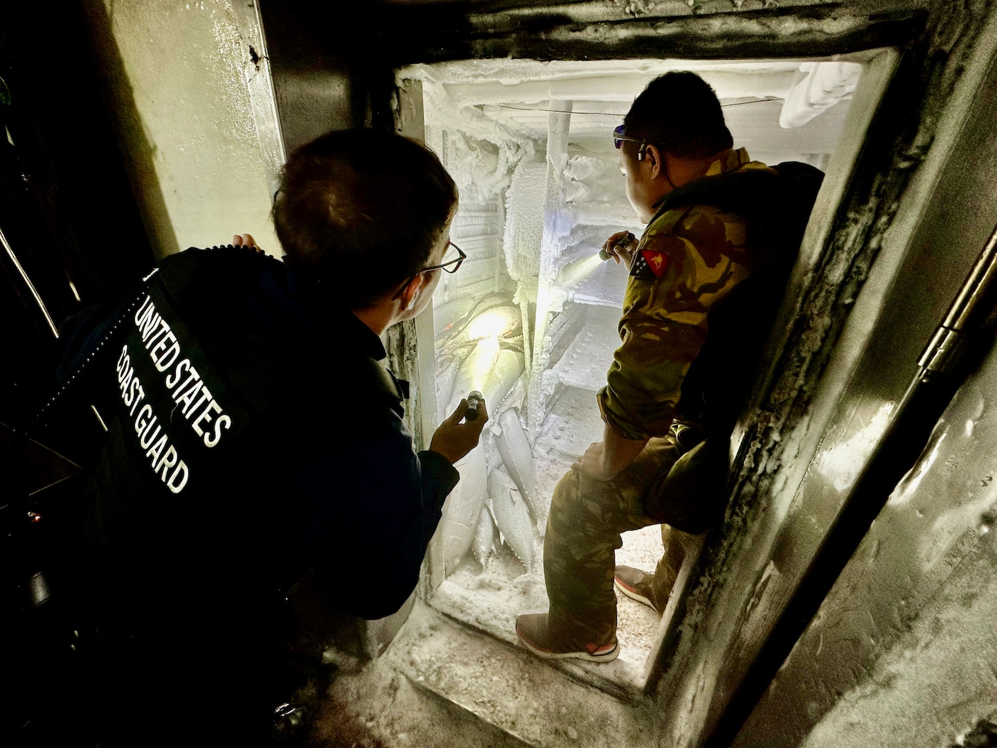 A member of a USCGC Myrtle Hazard (WPC 1139) boarding team and an officer from the Papua New Guinea Defence Force examine holds on a fisheries boarding on a People’s Republic of China-flagged fishing vessel during a combined patrol on Sept. 1, 2023, in the Coral Sea off Papua New Guinea. The U.S. Coast Guard was in Papua New Guinea at the invitation of the PNG government to join their lead in maritime operations to combat illegal fishing and safeguard marine resources following the recent signing and ratification of a bilateral maritime law enforcement agreement between the United States and Papua New Guinea. (U.S. Coast Guard photo by Chief Warrant Officer Sara Muir)