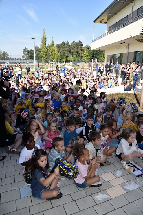Grafenwoehr Elementary School students sit in front of the school during its ribbon-cutting ceremony in Grafenwoehr, Germany, Sept. 12, 2023. Officials from the Department of Defense Education Activity, U.S. Army Corps of Engineers, U.S. Army Garrison Bavaria, 7th Army Training Command and more participated in the ceremony for the new school. (U.S. Army photo by Richard Puckett)