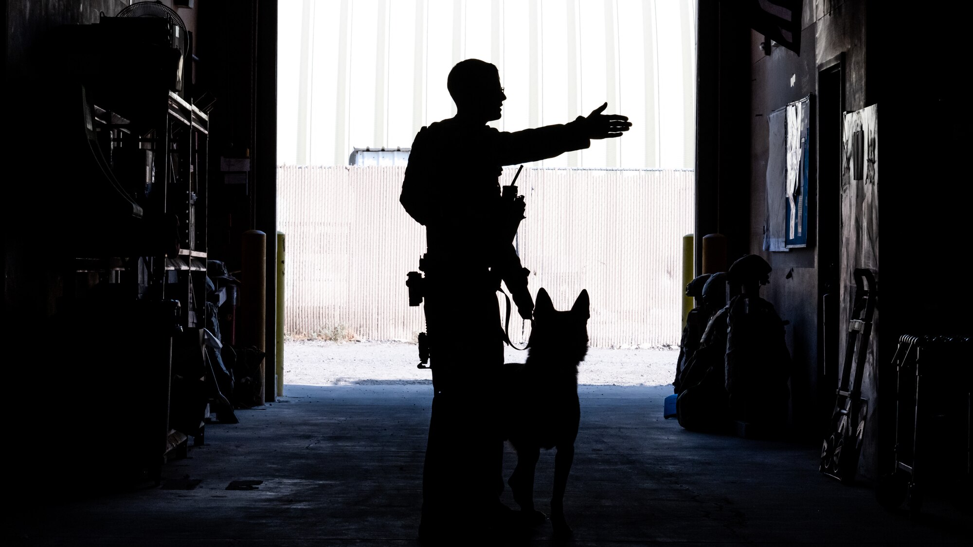 U.S. Air Force military working dog Lucky, Staff Sgt. Kyle Dean, 386th Expeditionary Security Forces Squadron MWD handler, search a warehouse for potential explosives during a training event at Ali Al Salem Air Base, Kuwait, Sept. 14, 2023. MWD handlers and their loyal K-9 partners make up a highly trained law enforcement team capable of critical drug and explosives detection skills that protect the installation. (U.S. Air Force photo by Staff Sgt. Kevin Long)