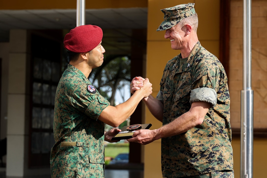 Singapore Guard Col. Tan Yukun Alan, left, commander of 7th Singapore Infantry Brigade gives U.S. Marine Corps Col. Thomas M. Siverts, commanding officer of Marine Rotational Force Southeast Asia (MRF-SEA), I Marine Expeditionary Force, a parting gift during the closing ceremony for Exercise Valiant Mark 2022 on Bedok Camp II, Singapore, Dec. 6, 2022. Valiant Mark is an annual, bilateral training exercise designed to enhance interoperability, build mutual defense capabilities, and strengthen military-to-military relationships between the U.S. Marine Corps and Singapore Armed Forces. MRF-SEA is an operational model developed by Marine Corps Forces Pacific that postures scalable I Marine Expeditionary Forces west of the International Date Line, conducts a series of planned subject matter expert exchanges, and advances security objectives shared with our Allies and Partners. (U.S. Marine Corps photo by Sgt. Jailine L. AliceaSantiago)
