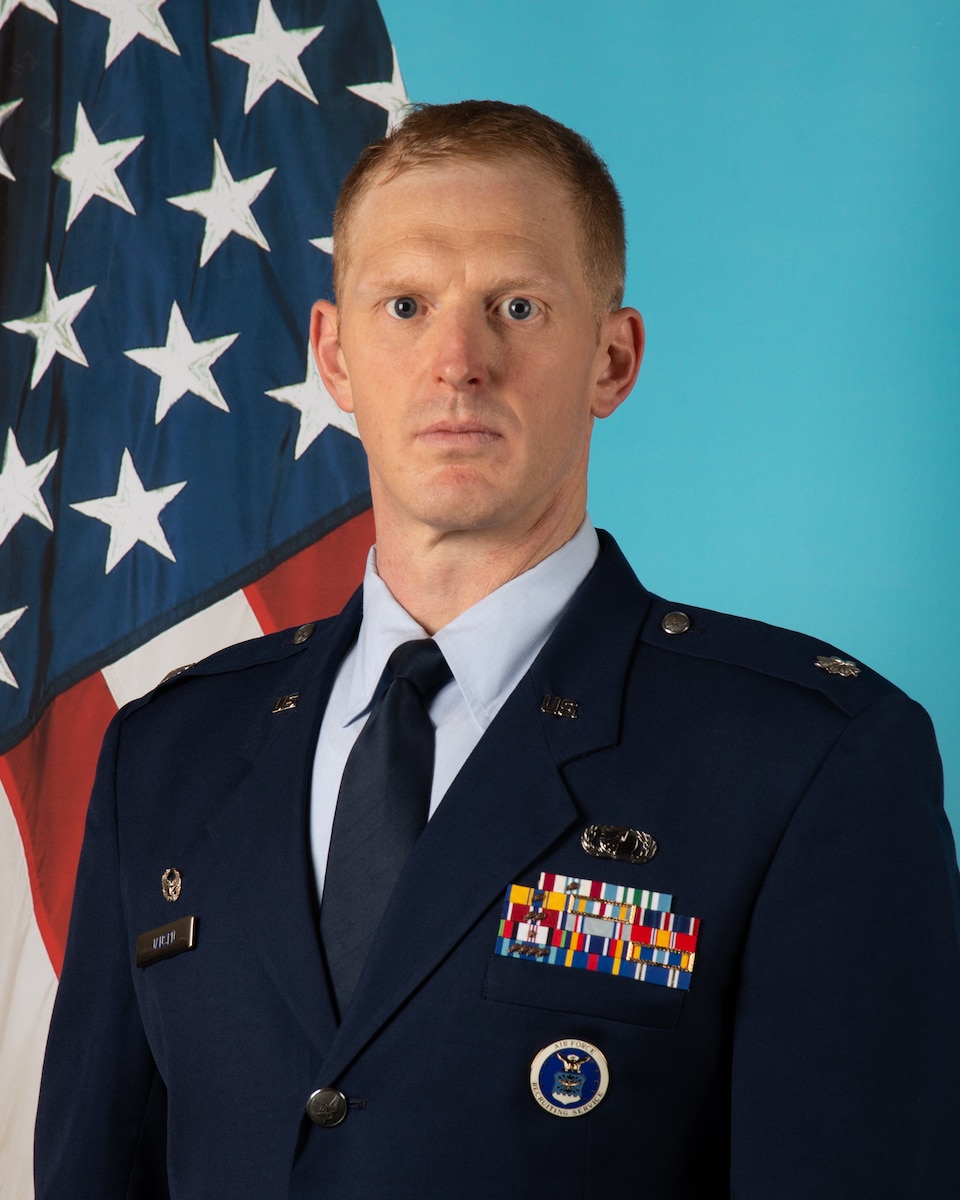 Man in uniform poses in front of U.S. flag