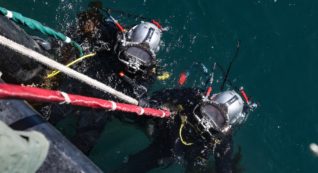 Construction Mechanic Second Class Anthony Macchia and Utilitiesmen First Class Adam Glista, assigned to Underwater Construction Team (UCT) 2, prepare to dive below the surface.