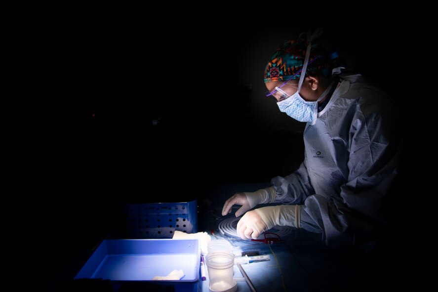 medical surgical technician prepares equipment in dark surgical suite in military treatment facility