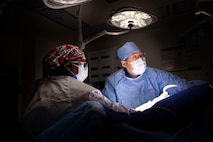 Army doctor in dark operating suite during surgery