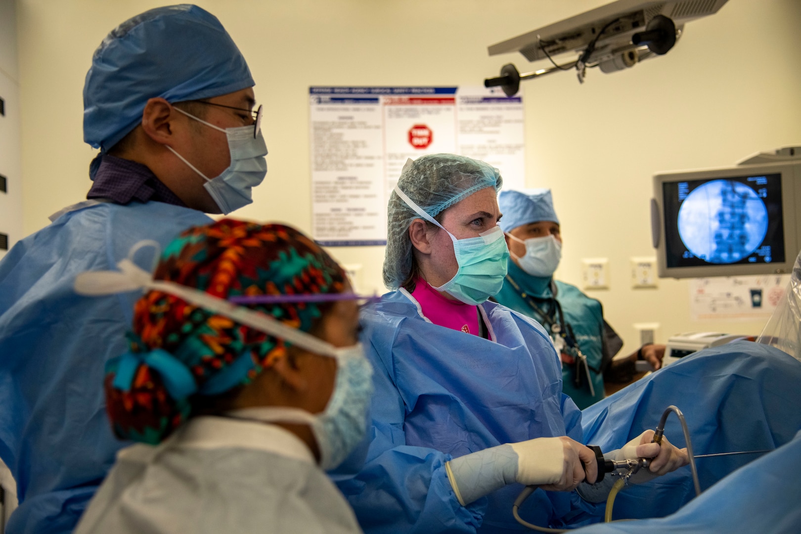 medical staff in personal protective wear (PPE) look at monitor during surgery