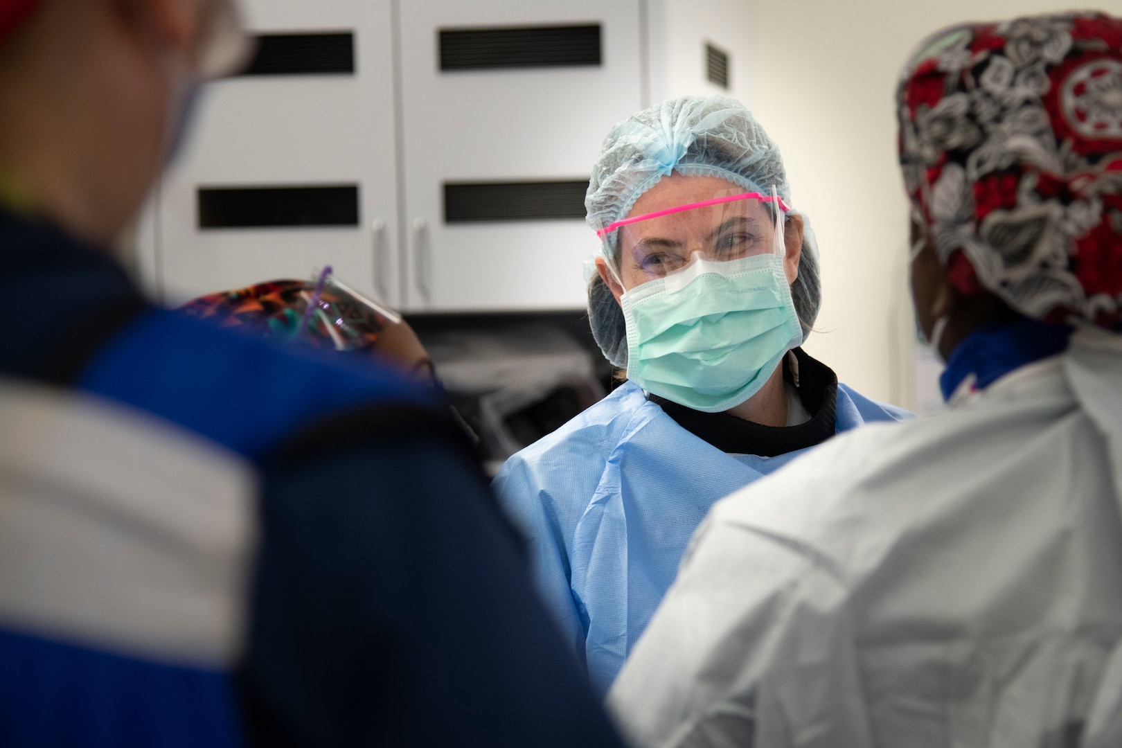 military doctor in personal protective equipment (PPE) leads huddle