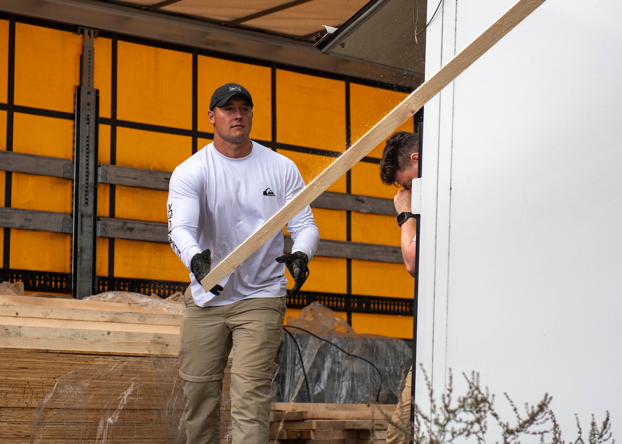 A man moves a wood plank.