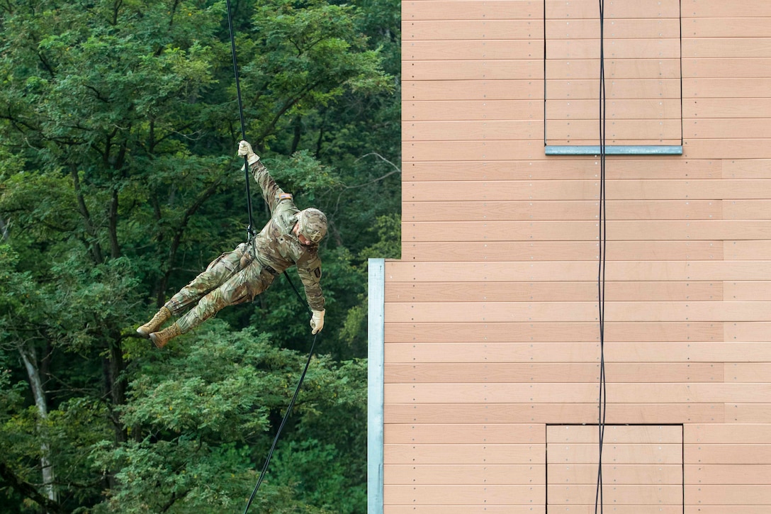 A soldier rappels down from a tower.