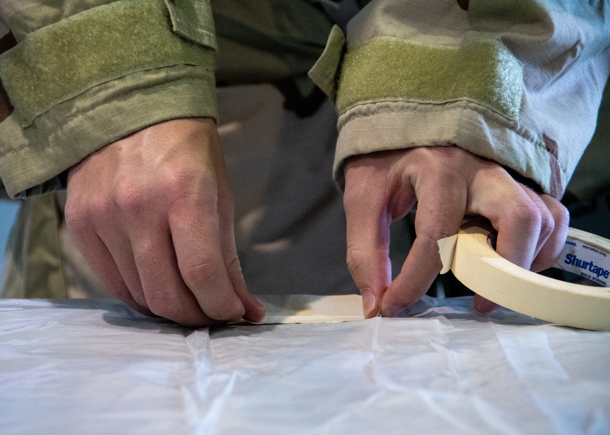 An airman applies standard tape simulating M9 Detector Tape to a tarp as part of a CBRN Defense Training held on Sept. 12, 2023, at Dobbins Air Reserve Base, Ga. M9 Detector Tape is used to detect the presence of nerve and mustard agents that aren’t detectable to the naked eye. (U.S. Air Force photo by Tech. Sgt. Joshua Kincaid)