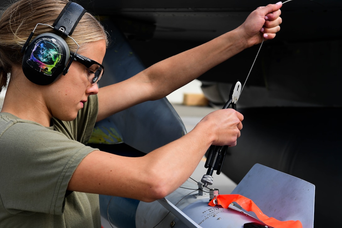 An airman loads an inert laser-guided bomb into an aircraft.