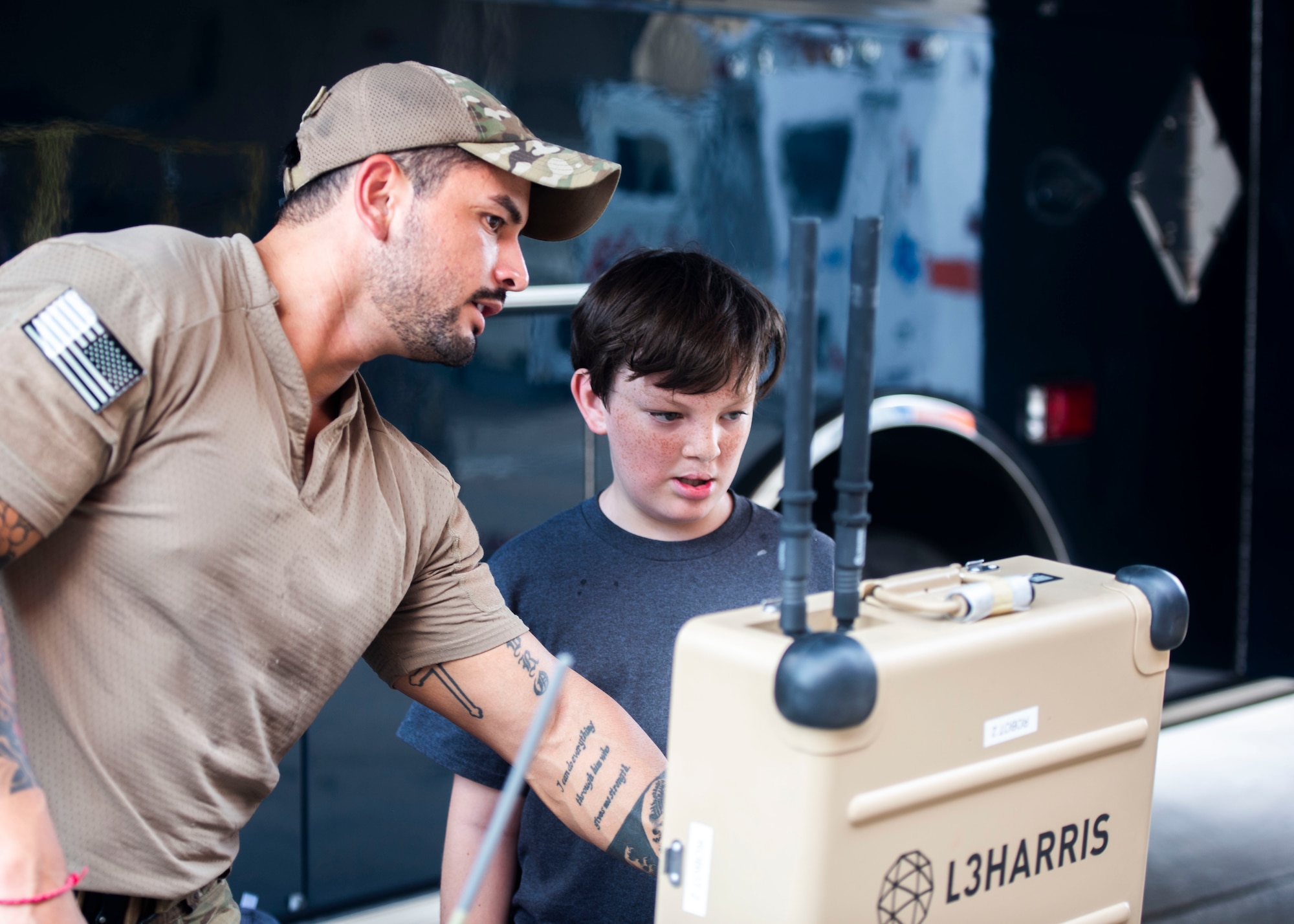 U.S. Air Force Staff Sgt. Jose Ramirez, 56th Civil Engineer Squadron explosive ordinance disposal technician, shows a military child various EOD equipment during the 15th annual Operation KIDS event Sept. 9, 2023, at Luke Air Force Base, Arizona.