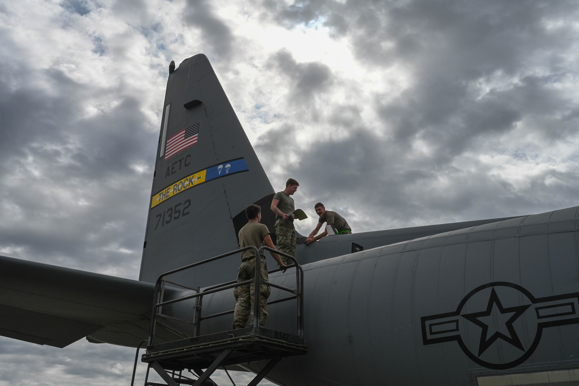 Airmen stand on an aircraft.