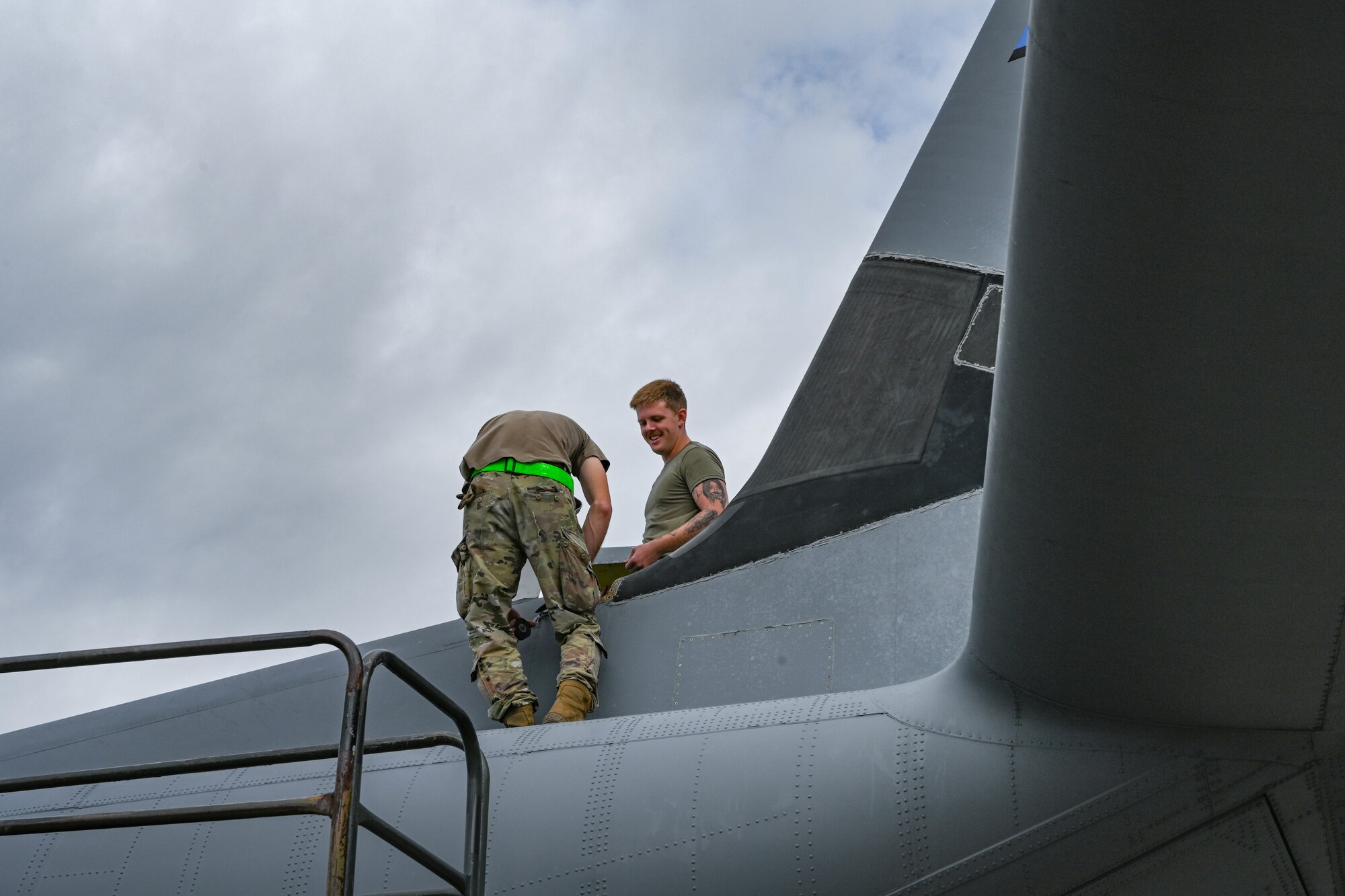 Airman stand on top of aircraft.