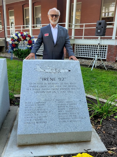 Man stands behind gray rectangular concrete memorial