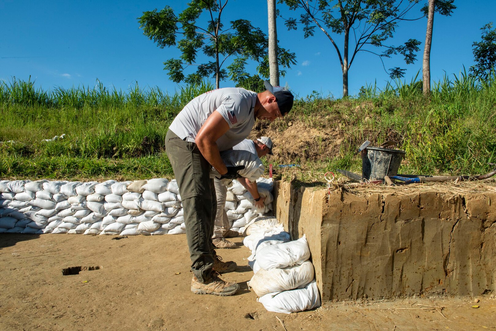 A person works places sandbags around an excavated area.