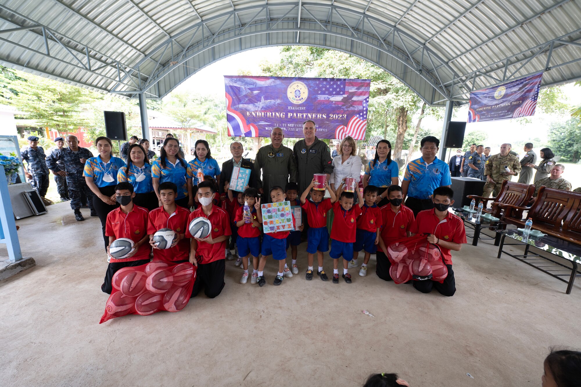 U.S. Air Force Brig. Gen. Gent Welsh, Washington Air National Guard Commander, and Royal Thai Air Force Group Captain Nat Kamintra, exercise director, stand with staff and children of Nong Phluang Yai primary school for a group photo, Korat, Royal Kingdom of Thailand, September 13, 2023. This community outreach partnership was a core part of the Enduring Partners 2023 exercise between the Kingdom of Thailand, the Washington and Oregon Air National Guard. The school visit gave a chance to connect U.S. military, Royal Thai military and the community of Korat. (U.S. Air Force photo by Tech. Sgt. Michael L. Brown)