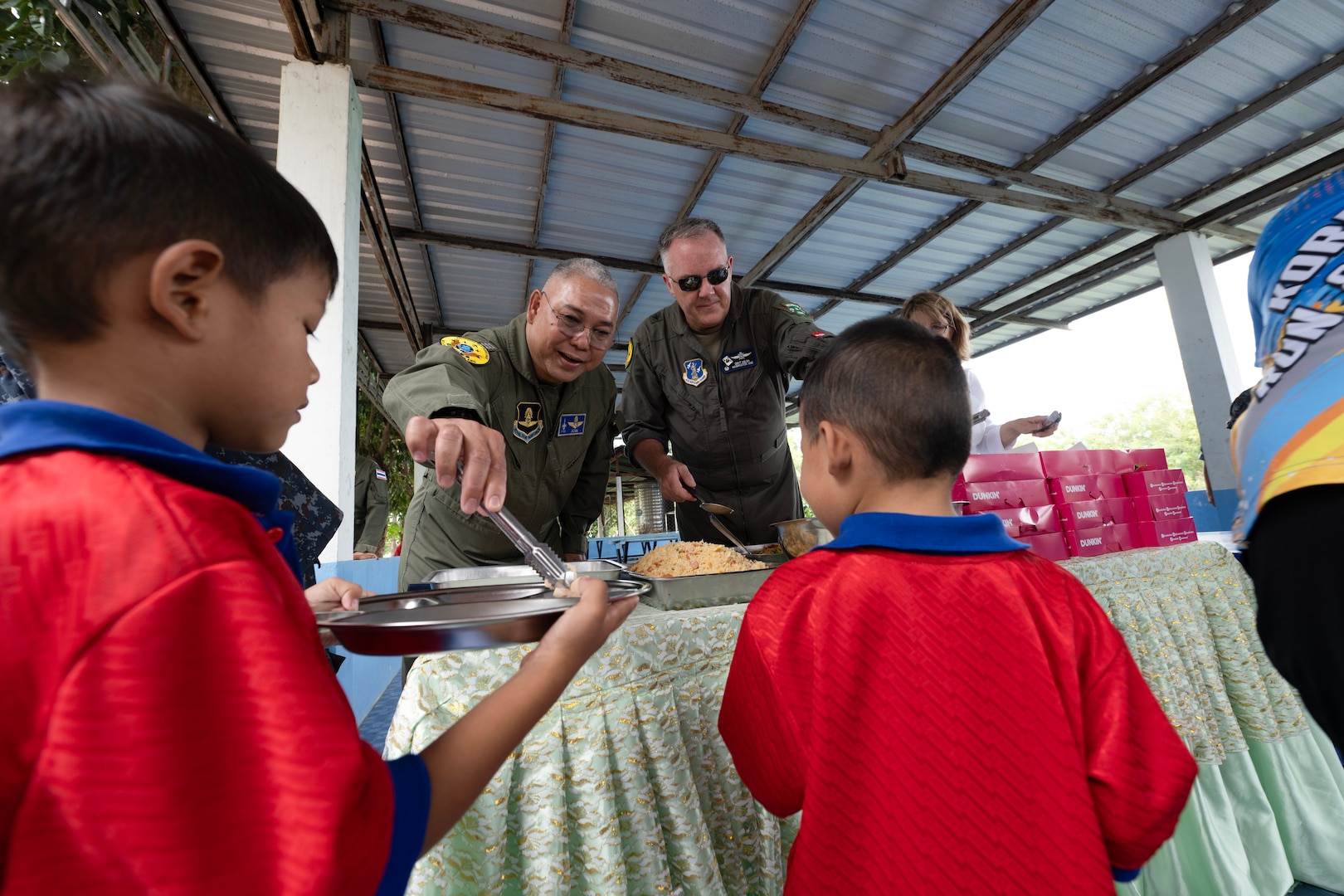 U.S. Air Force Brig. Gen. Gent Welsh, Washington Air National Guard Commander, and Royal Thai Air Force Group Captain Nat Kamintra, exercise director, serve lunch to children at Nong Phluang Yai primary school in Korat, Royal Kingdom of Thailand, September 13, 2023. This community outreach partnership was a core part of the Enduring Partners 2023 exercise between the Kingdom of Thailand, the Washington and Oregon Air National Guard. The school visit gave a chance to connect U.S. military, Royal Thai military and the community of Korat. (U.S. Air Force photo by Tech. Sgt. Michael L. Brown)