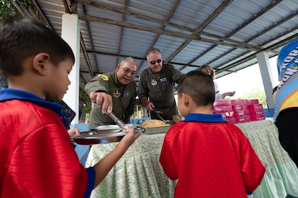 U.S. Air Force Brig. Gen. Gent Welsh, Washington Air National Guard Commander, and Royal Thai Air Force Group Captain Nat Kamintra, exercise director, serve lunch to children at Nong Phluang Yai primary school in Korat, Royal Kingdom of Thailand, September 13, 2023. This community outreach partnership was a core part of the Enduring Partners 2023 exercise between the Kingdom of Thailand, the Washington and Oregon Air National Guard. The school visit gave a chance to connect U.S. military, Royal Thai military and the community of Korat. (U.S. Air Force photo by Tech. Sgt. Michael L. Brown)
