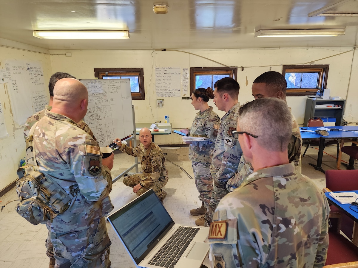 Command staff members gather around a white board to review the incoming aircraft schedule.