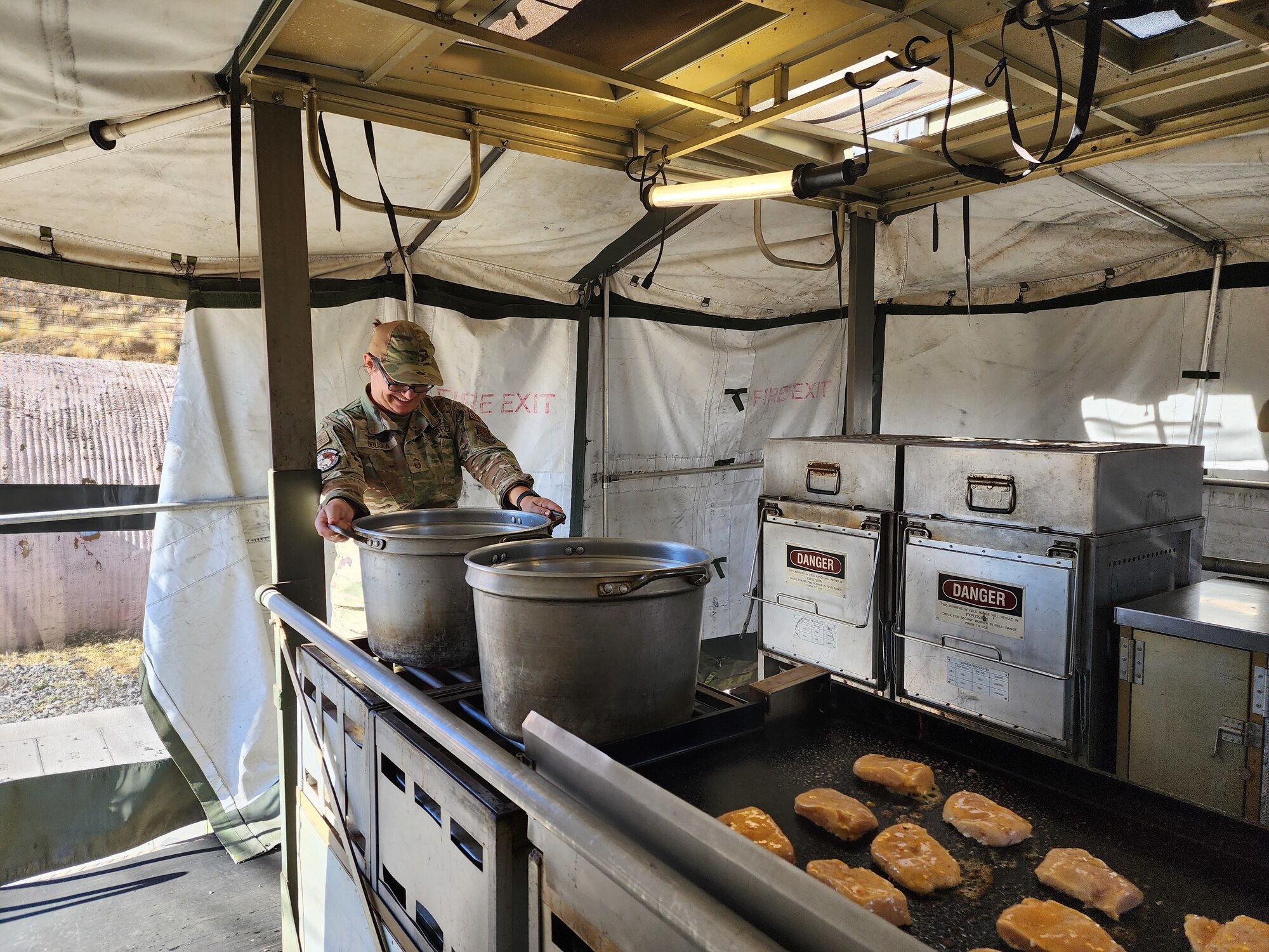 Female Airman places a large pot on to boil during dinner preparation.