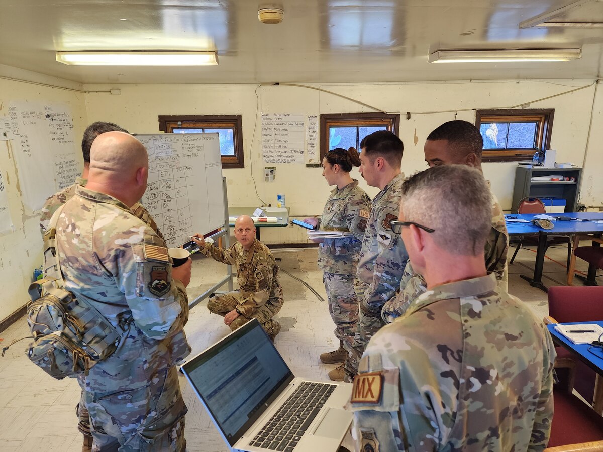 Command staff members gather around a white board to review the incoming aircraft schedule.