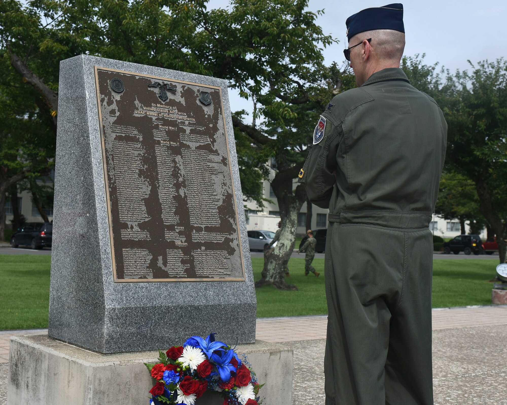 A military member stands in front of a memorial