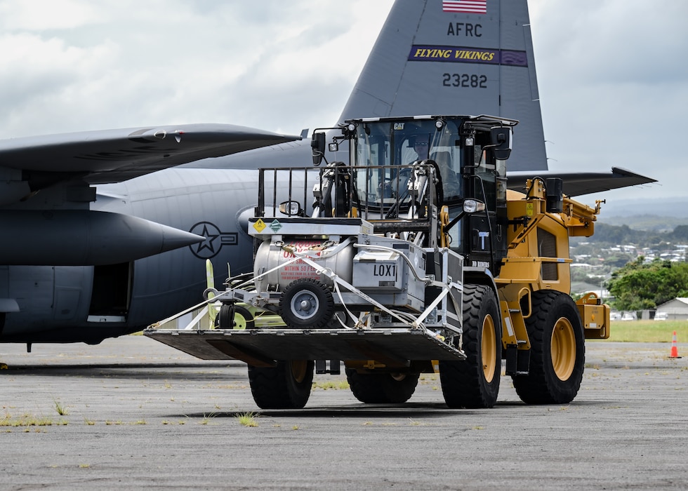 U.S. Air Force aerial port member operates a forklift carrying cargo to be loaded onto C-130H Hercules aircraft.
