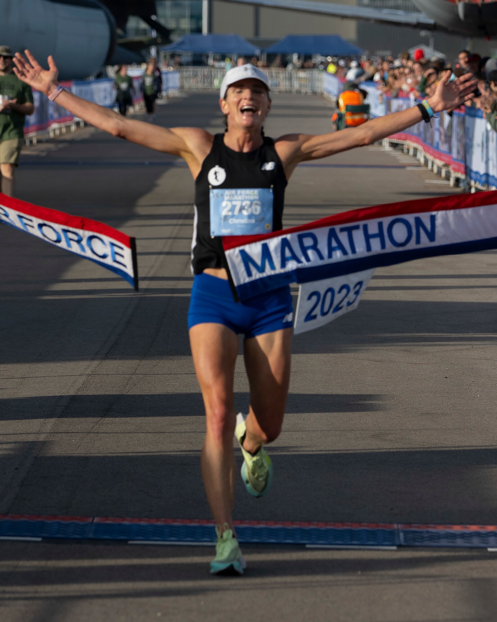 A woman stretches out her arms as she breaks a red, white and blue banner.