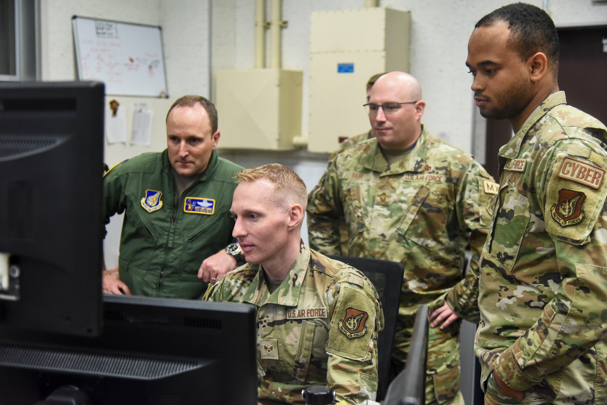 Military members watch an Airman work on a ticket.