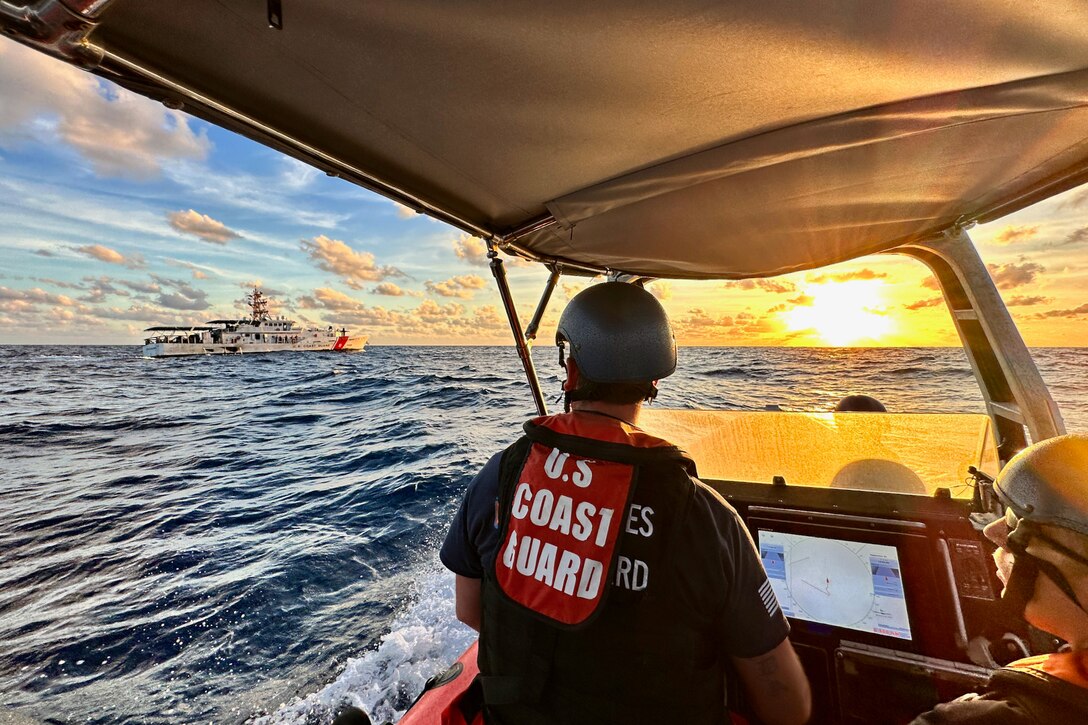 Coast Guard cutters patrol the ocean at twilight.