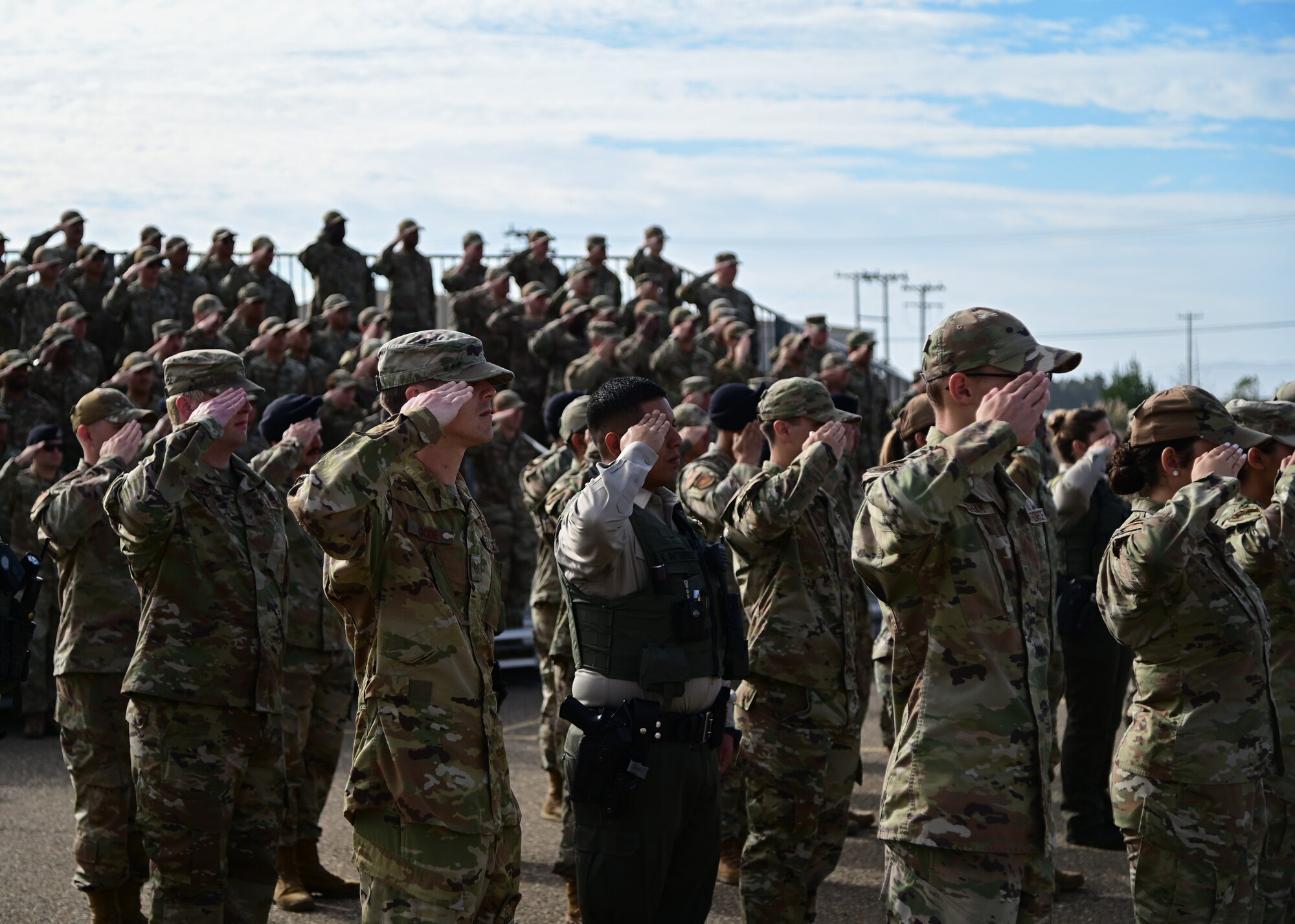 Members in uniform salute during a ceremony.