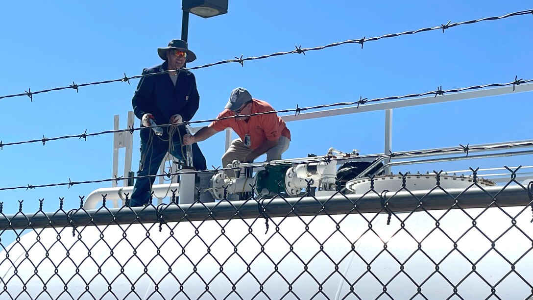 two men on top of a fuel tank