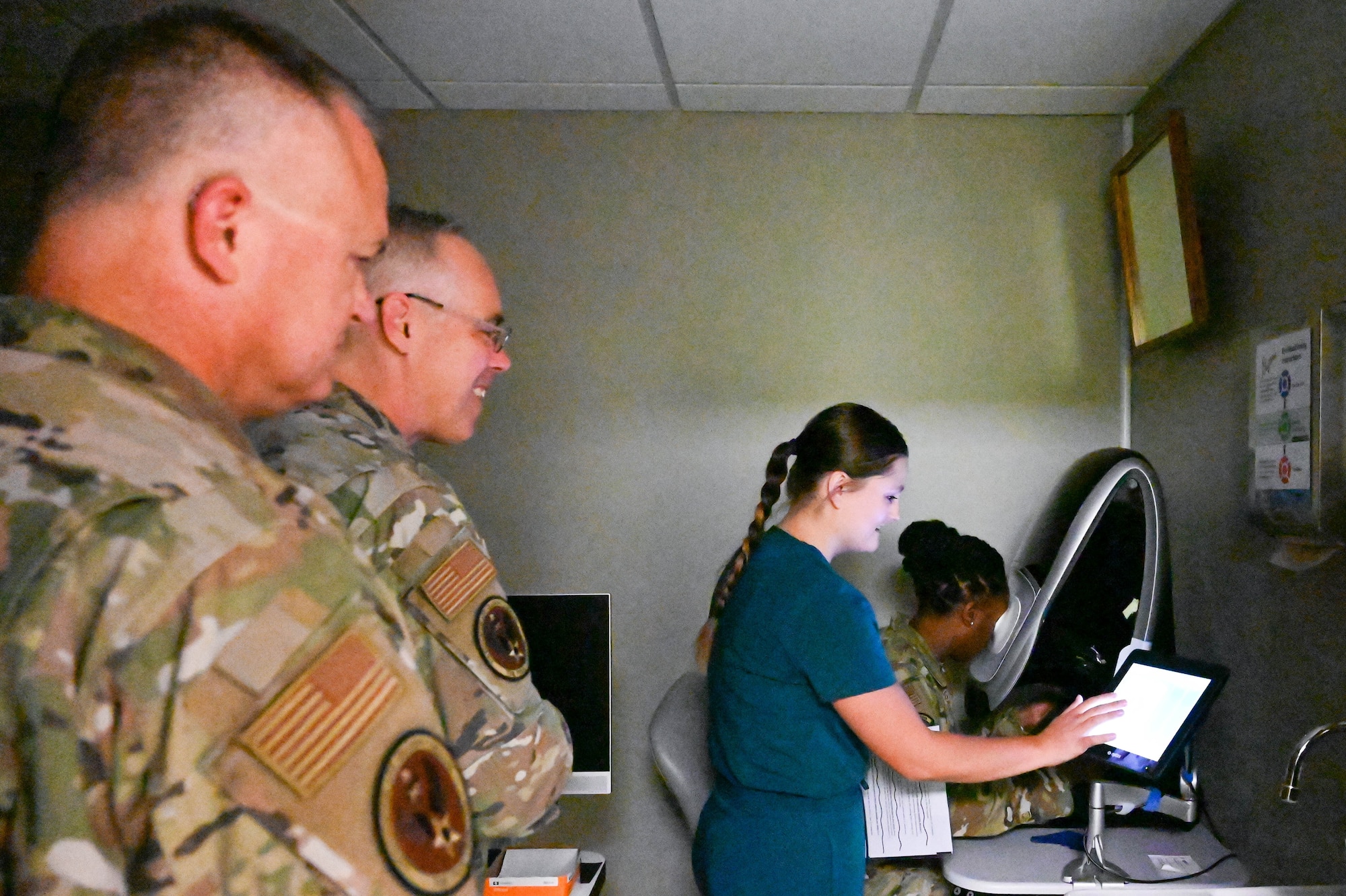 From left, U.S. Air Force Chief Master Sgt. Donald Cook, Air Education and Training Command (AETC) chief of enlisted medical force, and Col. Christopher Grussendorf, AETC surgeon general, take a closer look at ophthalmic equipment with Destiny Johnson, 97th Operational Medical Readiness Squadron optometry technician, during a tour at Altus Air Force Base, Oklahoma, Sept. 13, 2023. Members of the optometry clinic implemented a service that provides aircrew members with their first pair of glasses for free. (U.S. Air Force photo by Airman 1st Class Heidi Bucins)