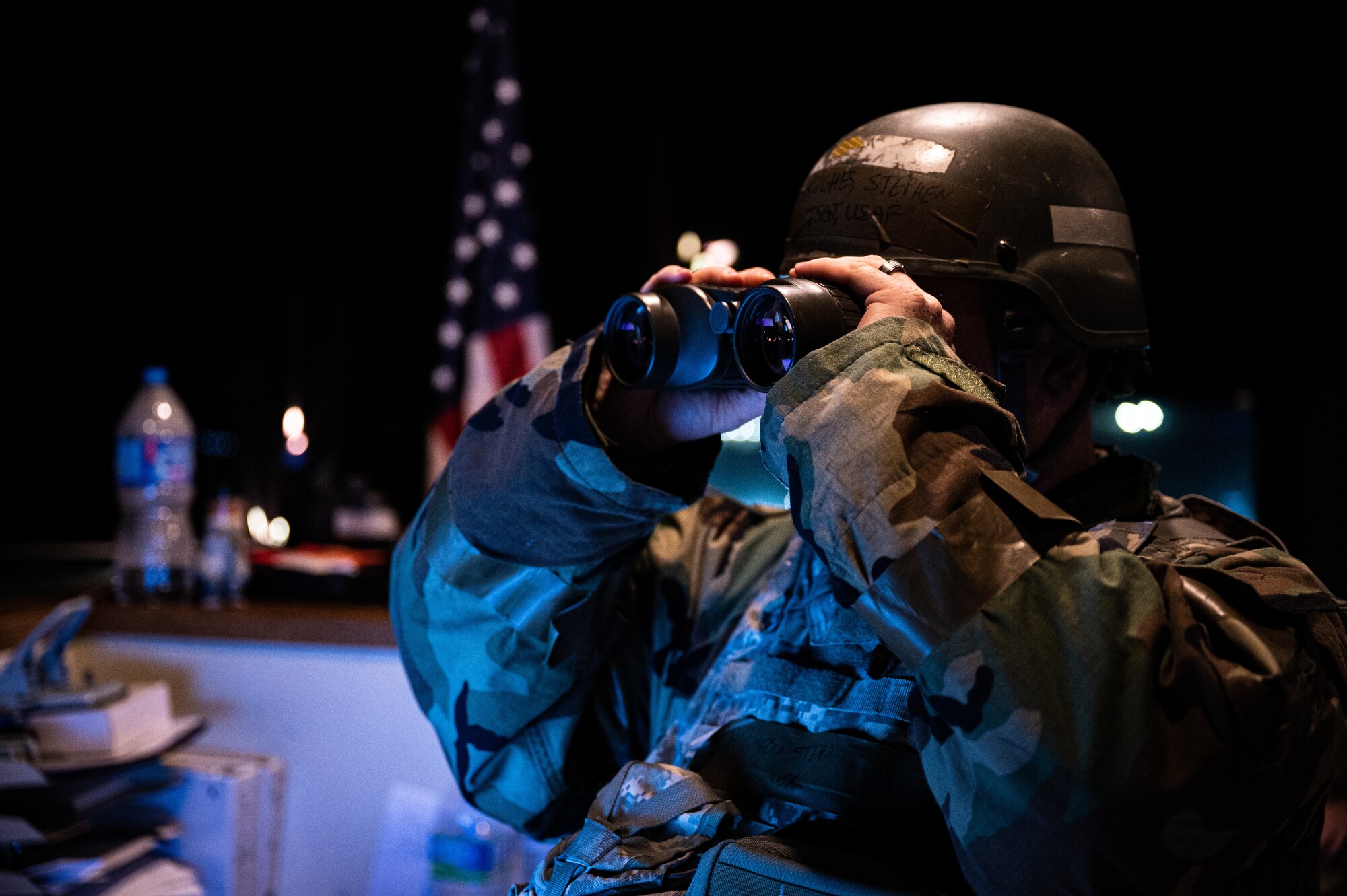 Technical Sgt. Stephen Hughes ses binoculars to view the airfield while wearing mission oriented protective posture gear during Beverly Pack 23-3.
