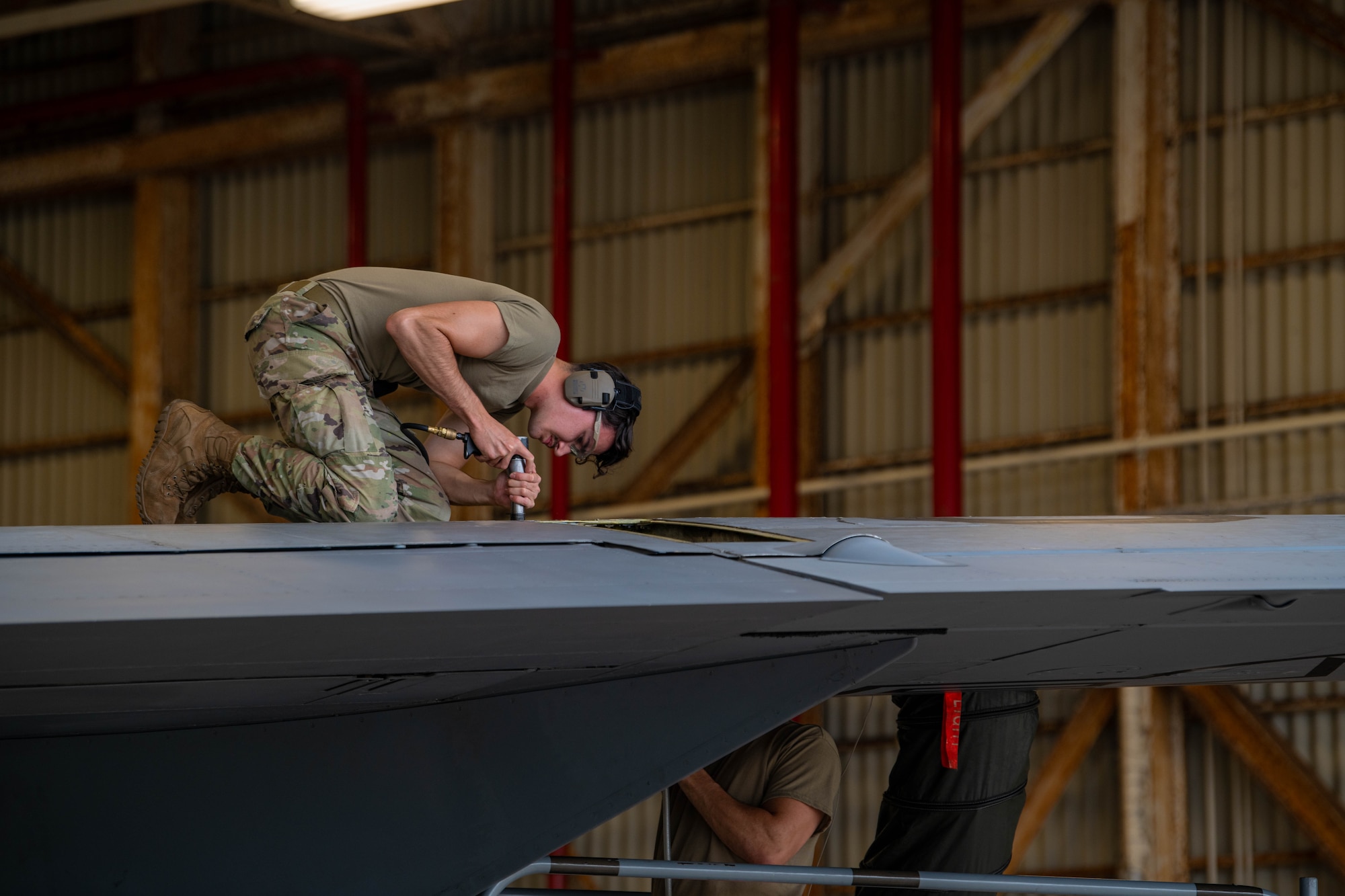 A1C Delaune bucking rivets on a KC-135 fuel tank.