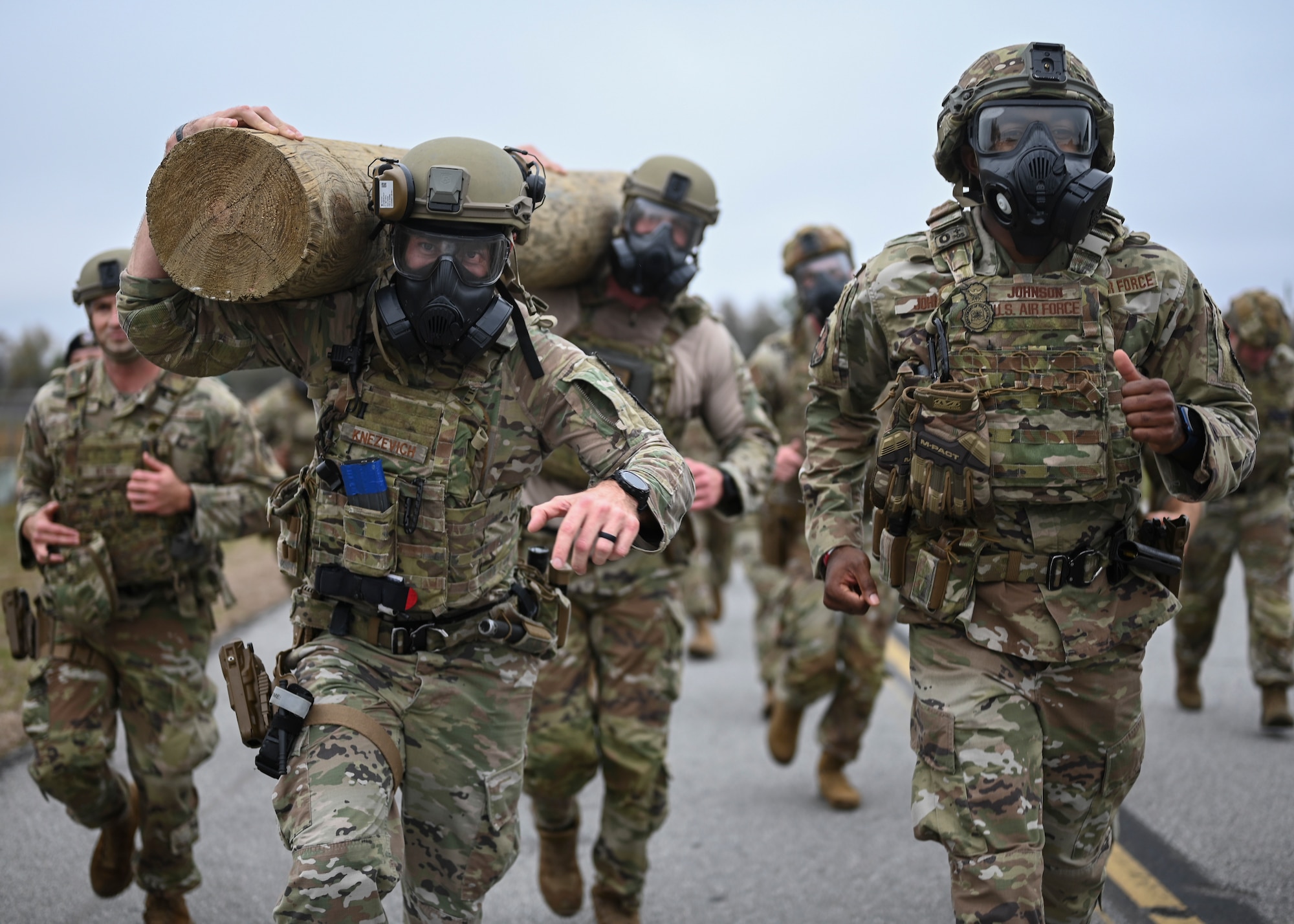 United States Airmen carry a log down the road.