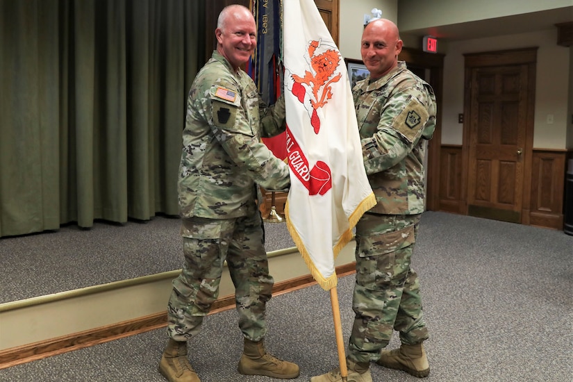 Maj. Gen. Mark Schindler, left, Pennsylvania's adjutant general, passes the colors to Command Sgt. Maj. Shawn Phillips, the Pennsylvania National Guard's incoming senior enlisted leader Sept. 5, 2023, at Fort Indiantown Gap. (U.S. Army National Guard photo by Sgt. 1st Class Zane Craig)