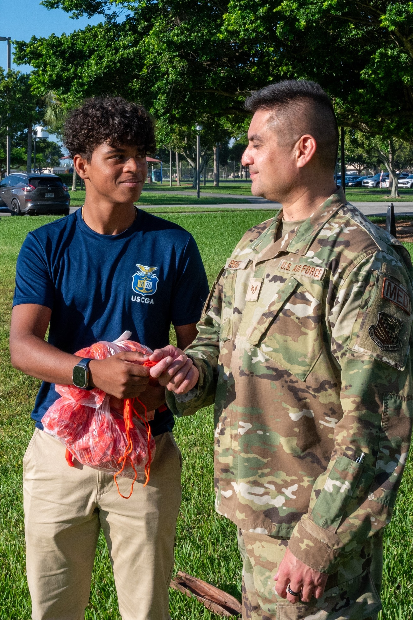 David Frazer of East Lyme High School, Connecticut, hands water safety whistles to Staff Sgt. Leonardo Perez of the 482d Medical Squadron at Homestead Air Reserve Base, Florida, September 9, 2023. The initiative underscores rising water safety concerns amid national heatwaves and the recent tragic drowning of two Airmen in June. (U.S. Air Force photo/Tech. Sgt. Paul Cook)