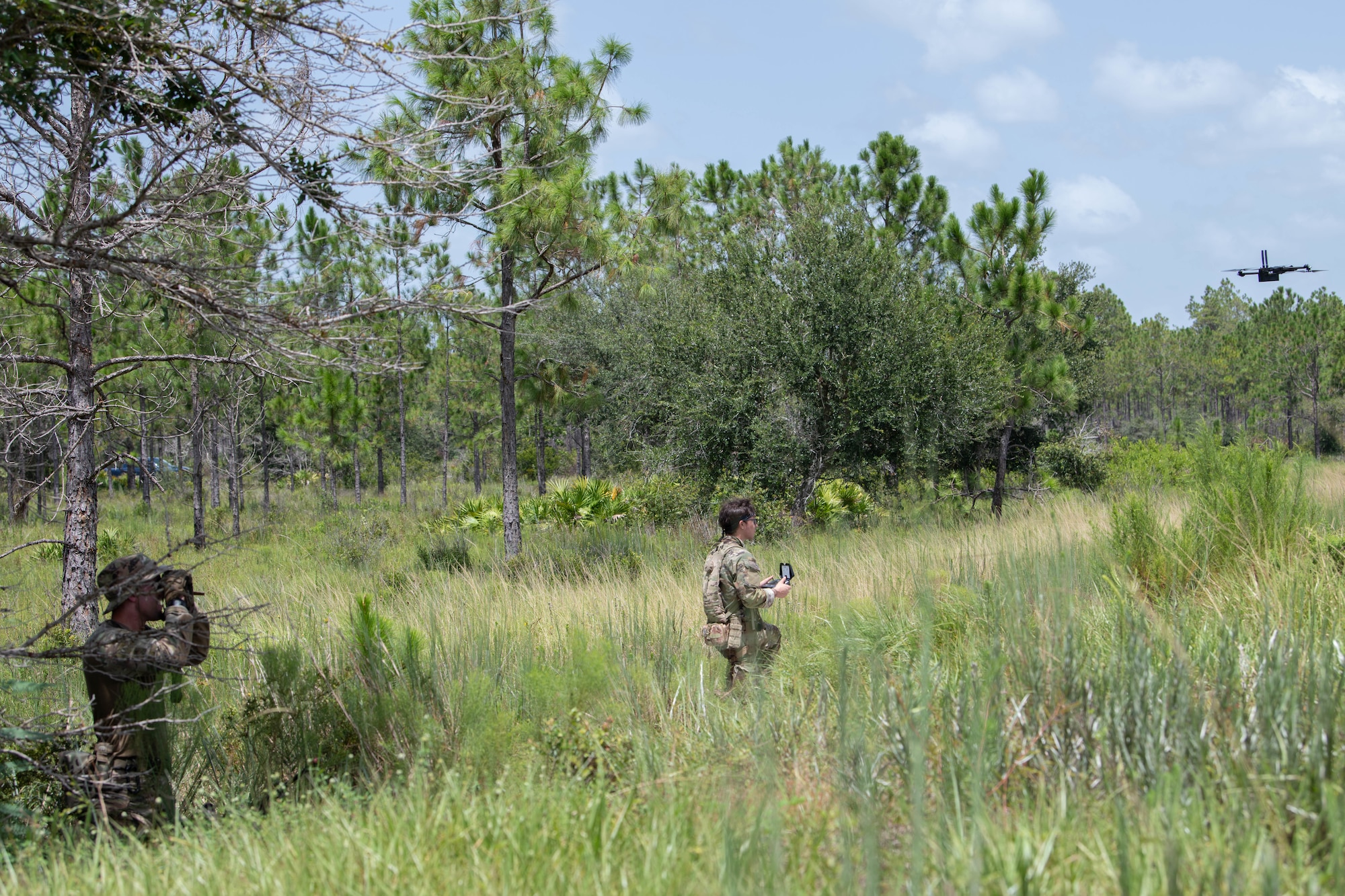 Two U.S. Air Force Airmen perform surveillance with binoculars and a small unmanned aerial system at a contingency location at Avon Park Air Force Range, Florida, August 22, 2023. 824th BDS members use sUAS to provide reconnaissance to promote security and safety of contingency locations. 824th BDS Airmen proved they were ready to provide security and support for upcoming Lead Wing operations through their mission readiness exercise. (U.S. Air Force photo by 1st Lt. Christian Little)
