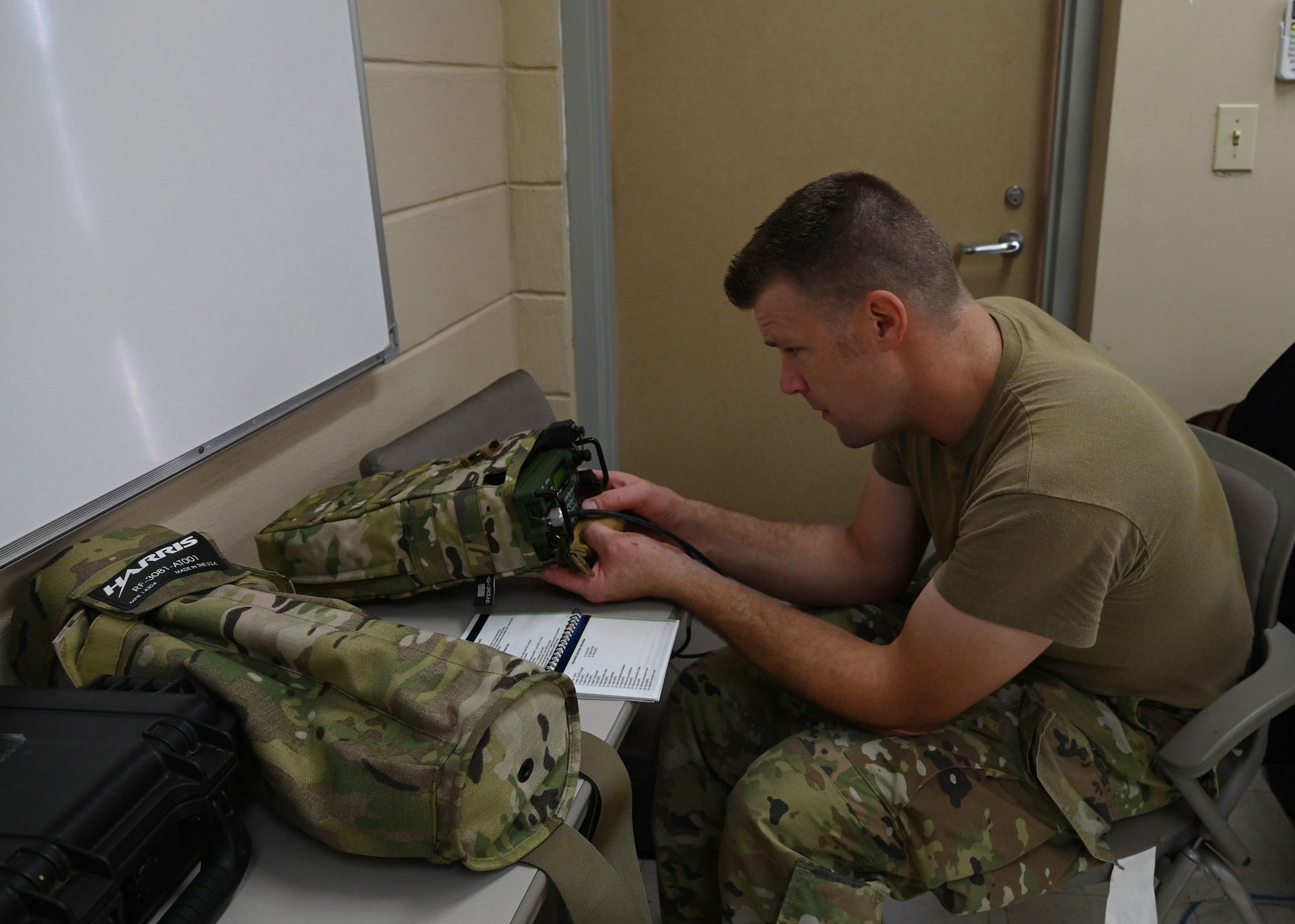 a man wearing a military uniform sets up communications equipment inside a building