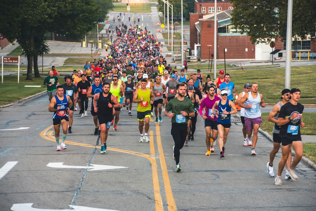 Hundreds of marathon runners run up a hill.
