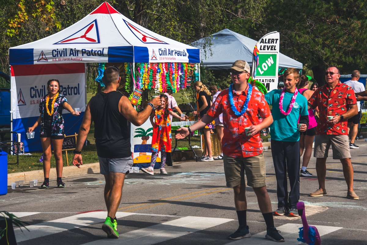 A runner takes a water cup from a man dressed up in luau attire.