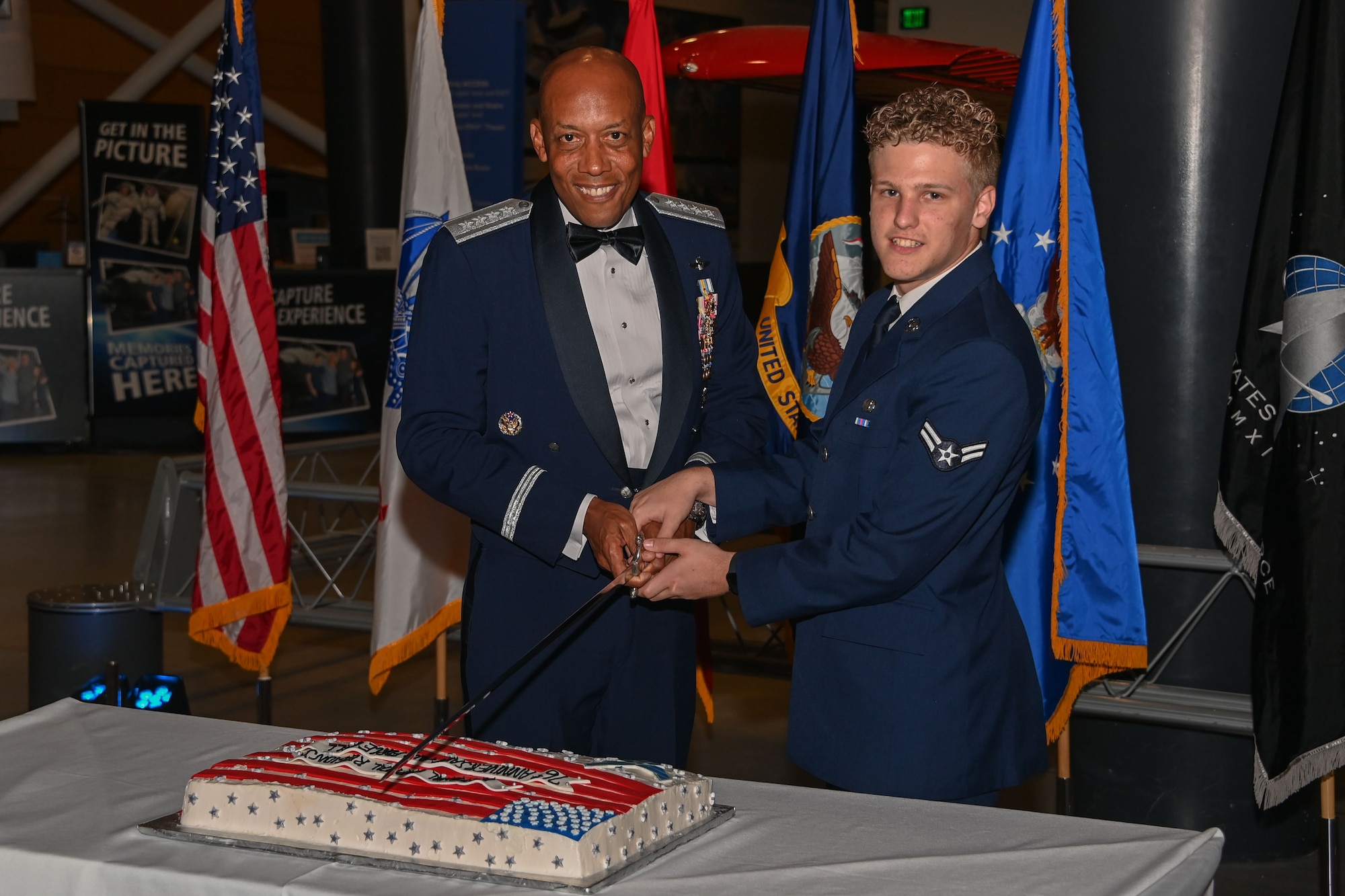 Two men in uniform cutting a cake.