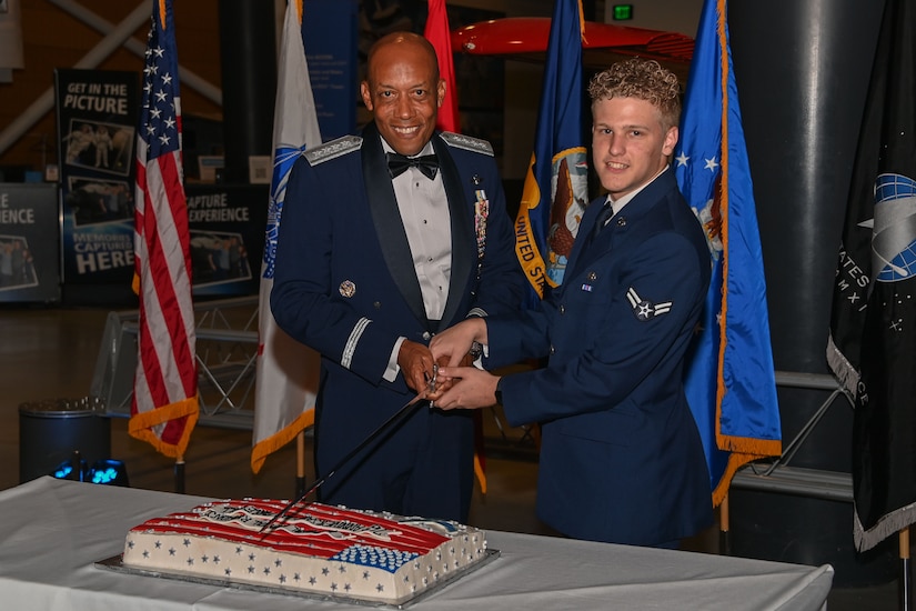 Two men in uniform cutting a cake.