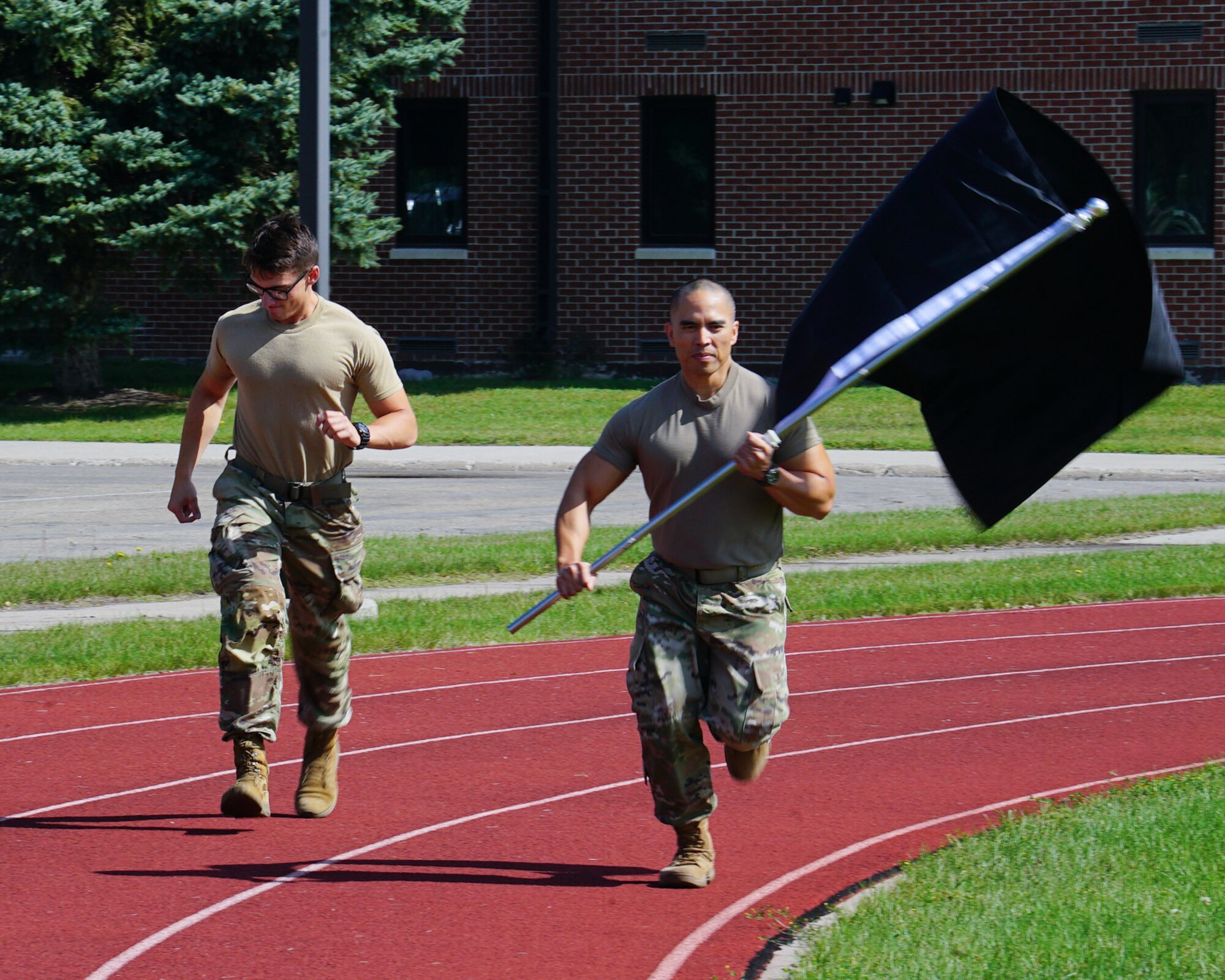 2 Airmen run down the track holding the POW/MIA flag