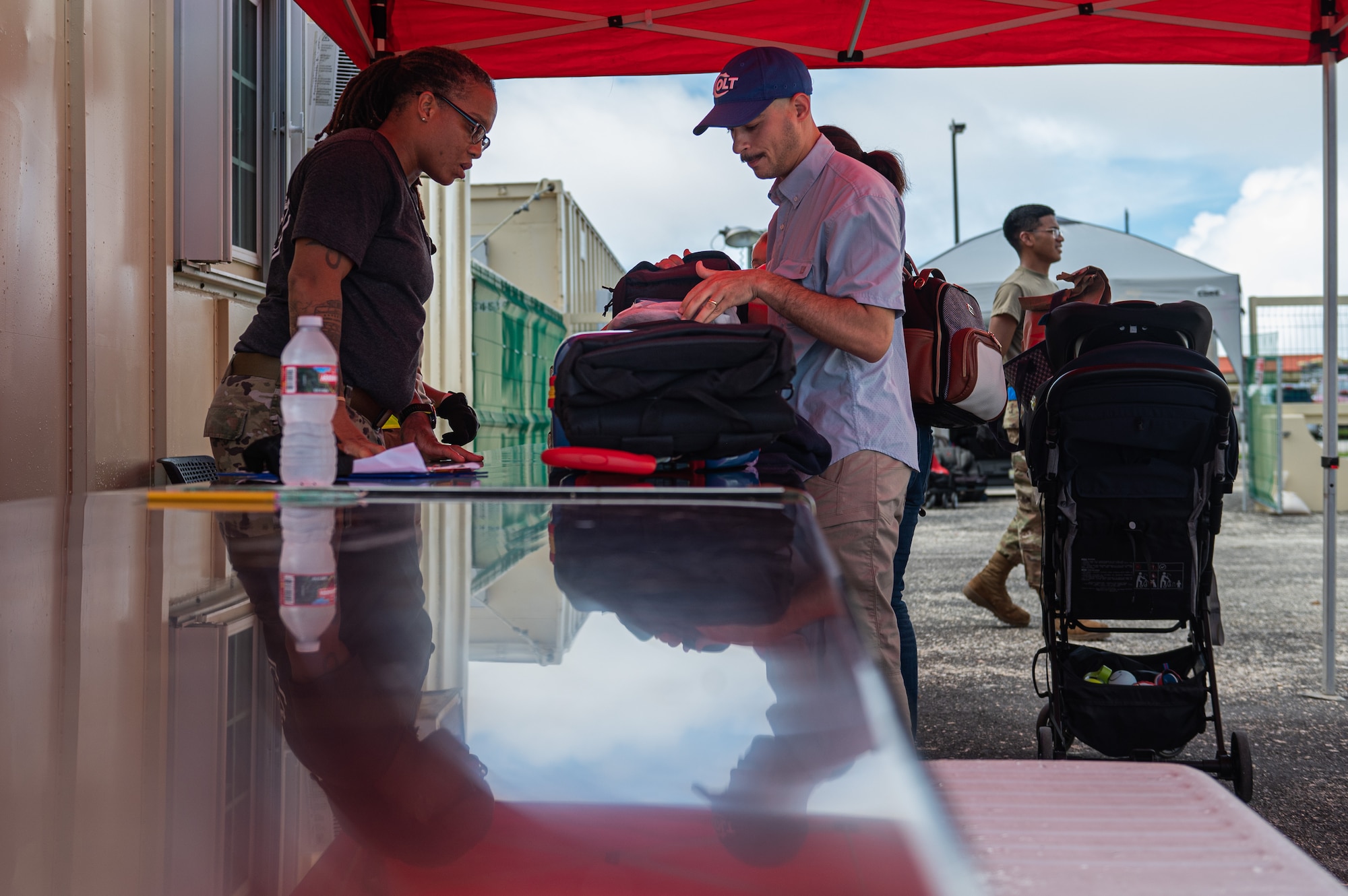 U.S. Air Force Staff Sgt. Denasha Mondy, 734th Air Mobility Squadron unit training manager, inspects a departing member’s luggage at Andersen Air Force Base, Guam, Sept. 17, 2023. The 734th Air Mobility Squadron created a makeshift passenger terminal, using portable office systems to support the freedom of movement for military personnel and their families after Typhoon Mawar. (U.S. Air Force photo by Staff Sgt. Suzie Plotnikov)