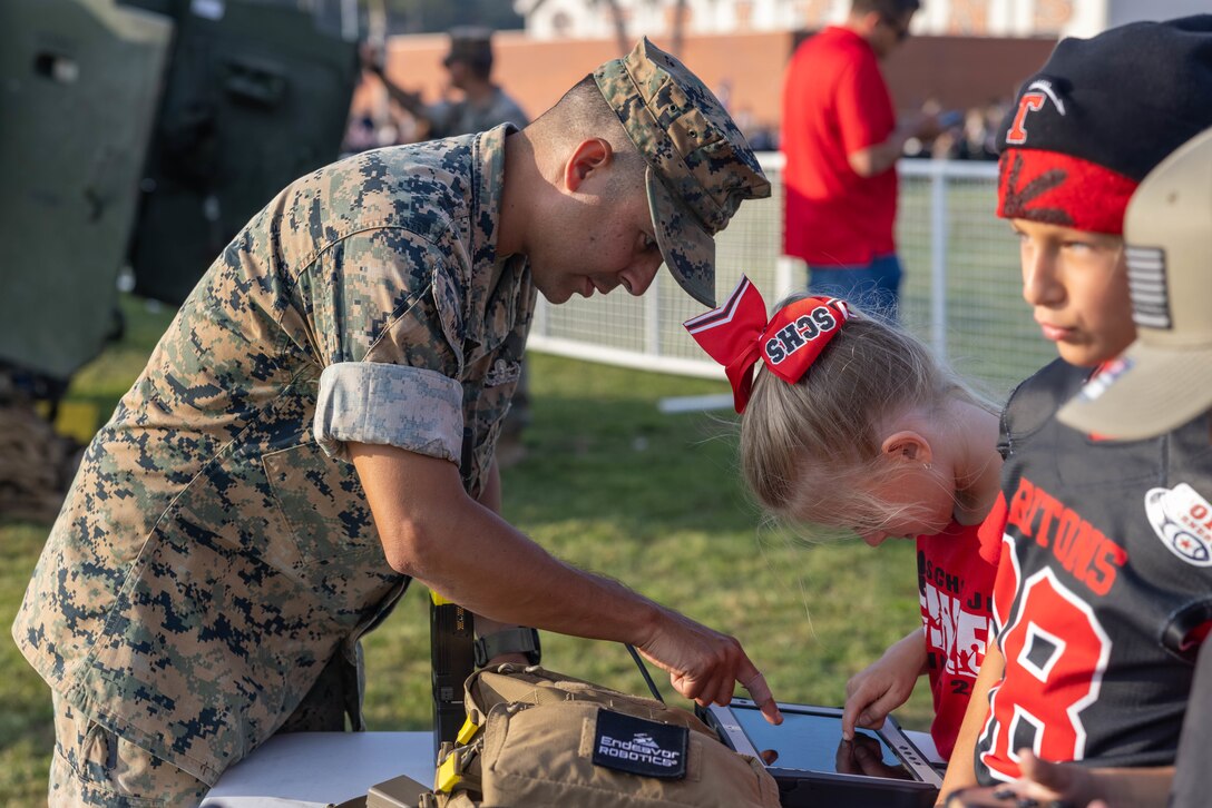 U.S. Marine Corps Gunnery Sgt. Paul I. Padilla, an explosive ordnance disposal technician with Marine Wing Support Squadron 372, Marine Aircraft Group 39, 3rd Marine Aircraft Wing, demonstrates how to operate the 310 Small Unmanned Ground Vehicle tablet to an attendee of San Clemente High School’s military appreciation day at Thalassa Stadium, San Clemente, California, Sept. 8, 2023.  Padilla demonstrated the equipment used by EOD Marines to locate, neutralize, and dispose of hazards with remote control robots and a bomb suit to students and parents of San Clemente High School. (U.S. Marine Corps photo by Lance Cpl. Jennifer Sanchez)